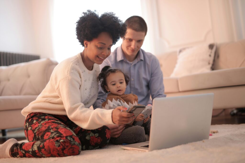 A joyful family of three enjoying togetherness while using a laptop indoors. Nature based learning in early childhood childcare development center